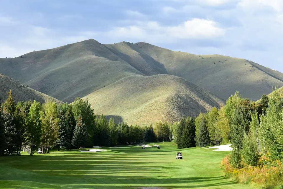 A green fairway on the Sun Valley golf course in Idaho, backed by mountain slopes and stands of trees